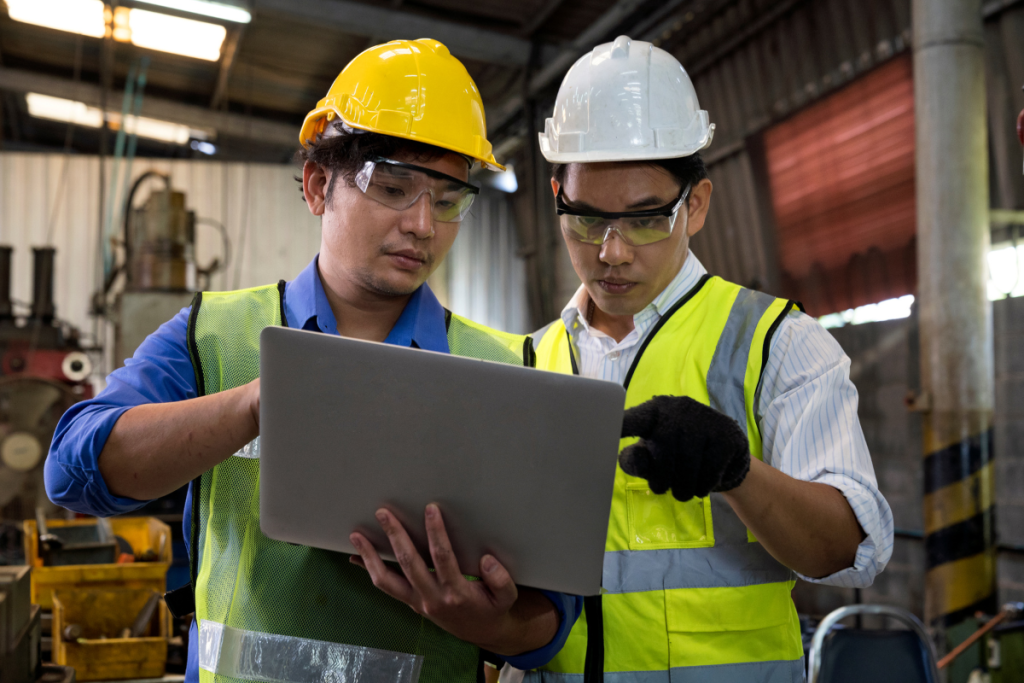 Production lead and worker at manufacturing facility reviewing data compliance procedure
